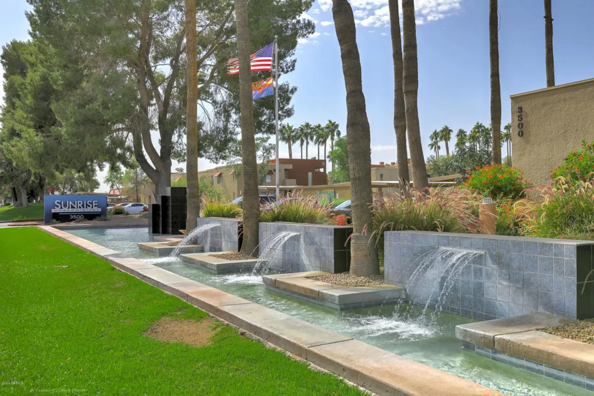 A peaceful exterior scene with water features, clear signage, and landscaped surroundings. The inviting pathway and tranquil atmosphere make it an ideal spot for a relaxing walk or casual outing with a pet. The presence of signage hints at well-maintained, community-oriented outdoor areas.