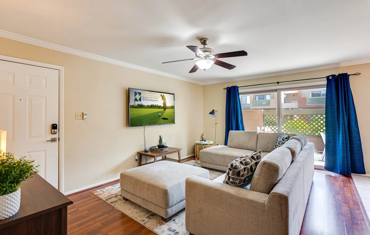 A comfortable living area centered around a plush sofa, large TV, curtains, and a coffee table. The room exudes warmth and is well-suited for relaxing, socializing, or watching the game with friends.
