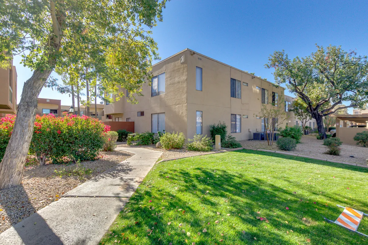 A wide exterior shot capturing green grass, flowering shrubs, and the architectural details of the building. The space feels open and fresh—a place for relaxing outdoors or taking a break from work.